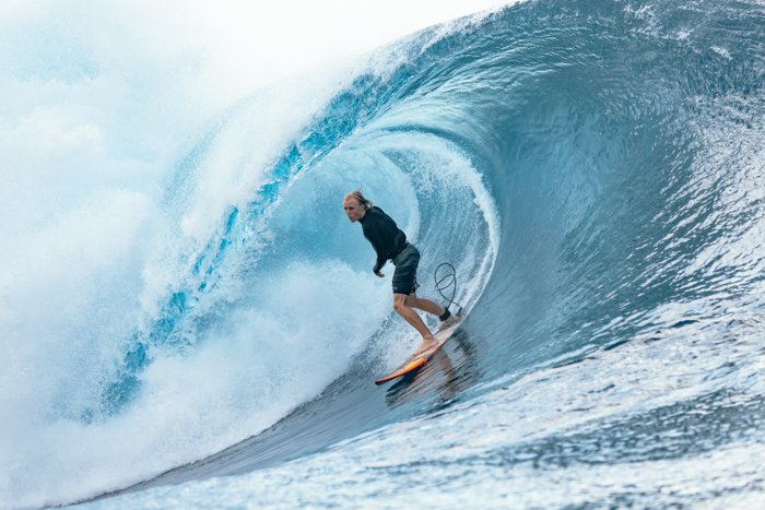 fotografía de aventura de un surfista montando una ola azul