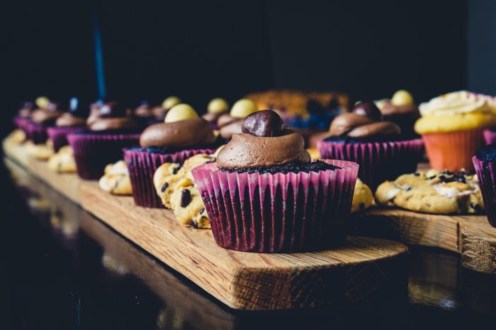 Un primer plano de cupcakes en una fila sobre una mesa, con papel de cupcake morado oscuro