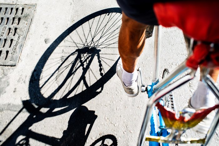 Un primer plano de un ciclista pedaleando con sombras proyectadas sobre el suelo de piedra, el mejor momento del día para las fotos