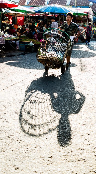 Un hombre empujando un carrito a través de un mercado durante el mejor momento para tomar fotos al aire libre con luz natural