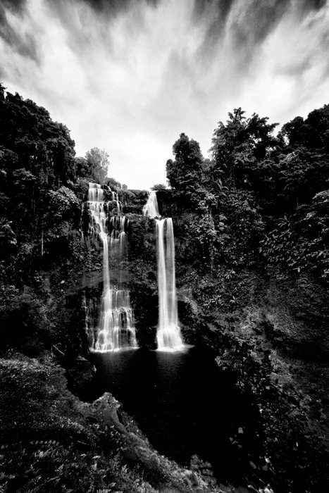 Disparo en blanco y negro de larga exposición de una cascada, vista de retrato