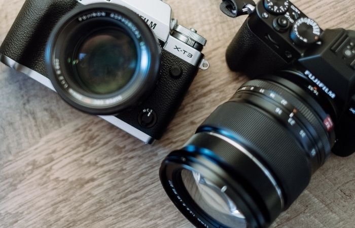 una cámara analógica y digital colocada sobre una mesa de madera