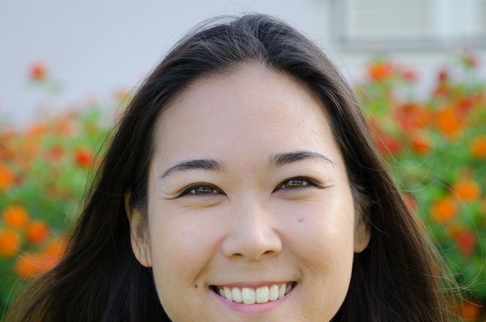 Captura de pantalla recortada de una mujer asiática sonriente en un campo de flores rojas