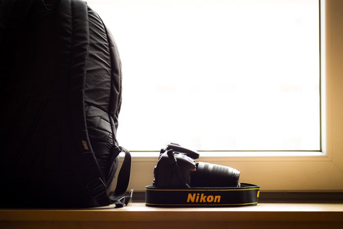 Una cámara Nikon colocada en un estante al lado de una mochila para cámara