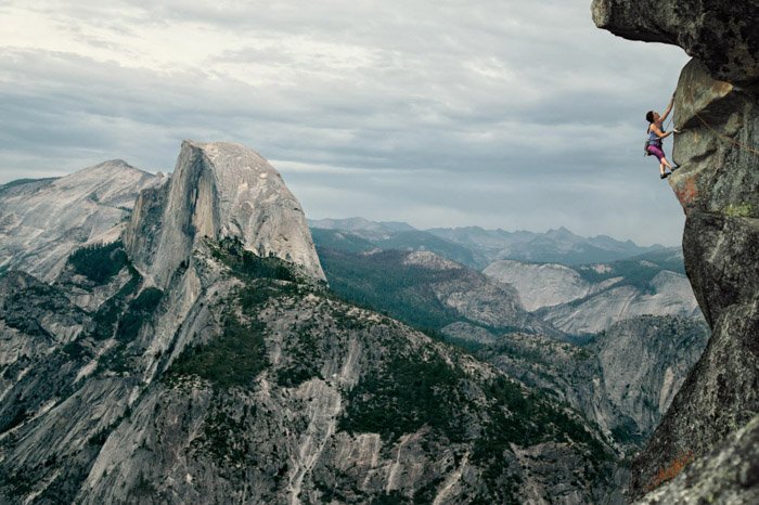 Fotografía de aventura de una mujer escalando en un vasto paisaje montañoso por Andy Bardon.