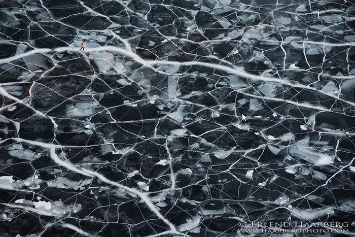 Fotografía de una figura caminando por un paisaje helado texturizado de Erlend & Orsolya Haarberg.
