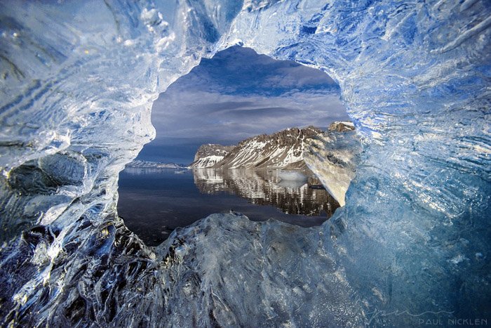 Un paisaje marino fotografiado a través de un agujero en el hielo por Paul Nicklen.
