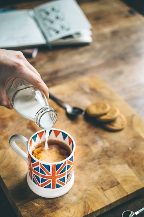 La leche se vierte en una taza de café con una bandera del Reino Unido utilizada como accesorio de fotografía de alimentos