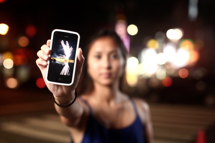 una niña sosteniendo un iPhone al aire libre por la noche