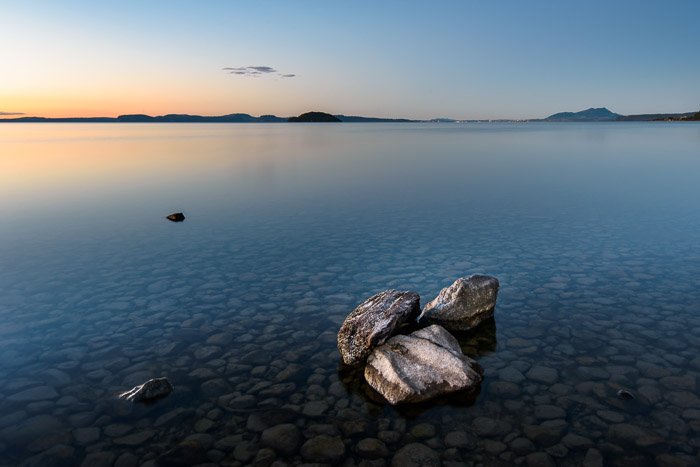 Un grupo de rocas en un mar tranquilo al atardecer.  Composición de fotografía de paisaje