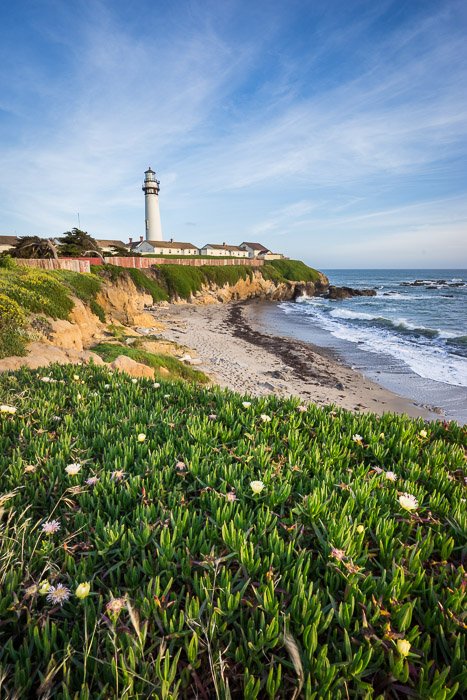 Una foto luminosa de un paisaje costero con un faro al fondo.  Composición de fotografía de paisaje