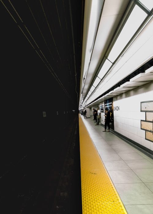 El oscuro túnel del metro en una mitad y la gente que espera en el andén brillante