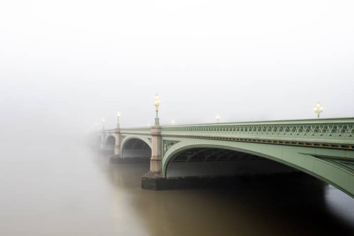 Toma atmosférica de un puente verde que desaparece en la niebla