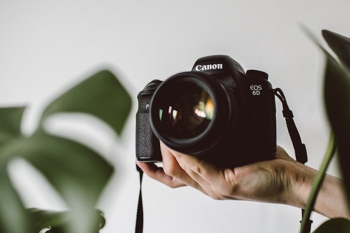 una mano sosteniendo una cámara Canon DSLR - herramientas de negocios de fotografía