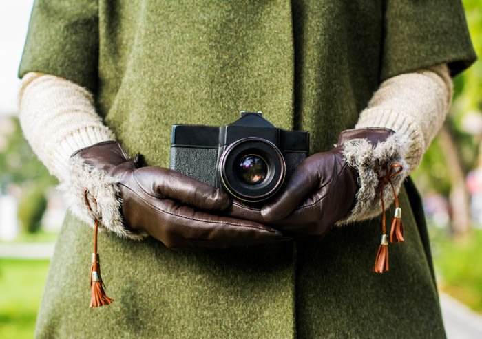 una imagen de una persona sosteniendo una cámara con un par de guantes marrones en