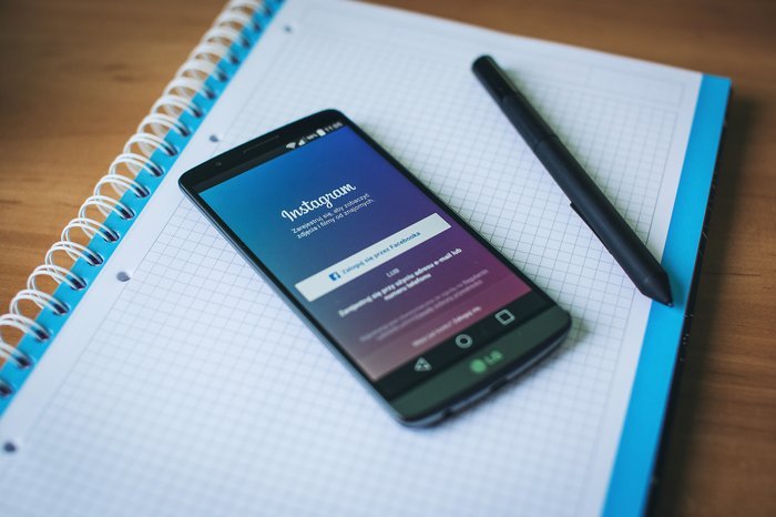 Un teléfono inteligente abierto en Instagram, encima de un cuaderno