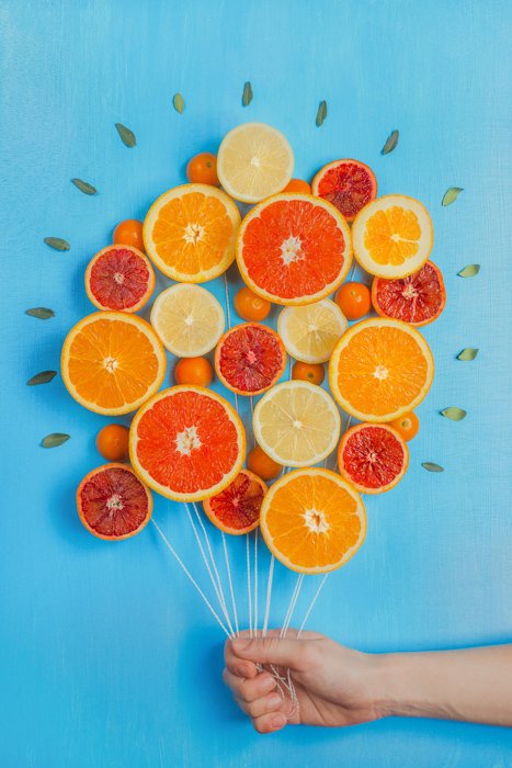 Un arreglo de ideas de fotografía de naturaleza muerta de naranjas hechas para parecerse a un montón de globos, sobre fondo azul
