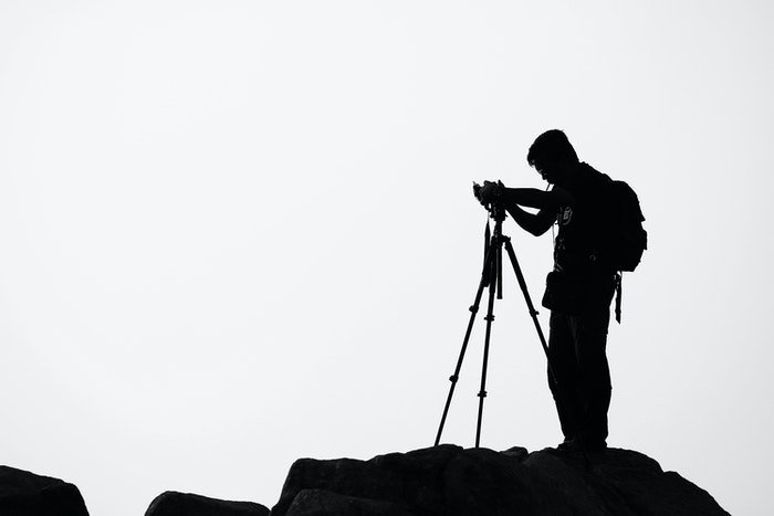 Silueta de un fotógrafo configurando su cámara en un trípode