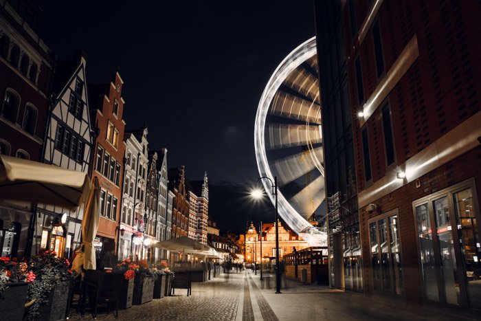 Una escena de la calle por la noche con una rueda de la fortuna en movimiento capturada con una cámara de lapso de tiempo