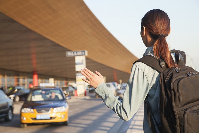 una imagen de una mujer llamando a un taxi en el aeropuerto
