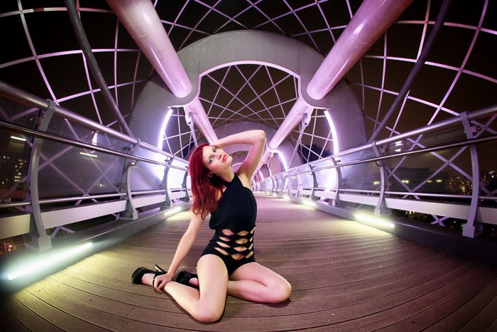 Una sesión de fotos urbana de una modelo femenina posando en un puente bajo luces de neón