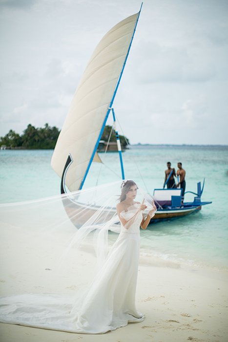 Una novia posando con un barco al fondo.