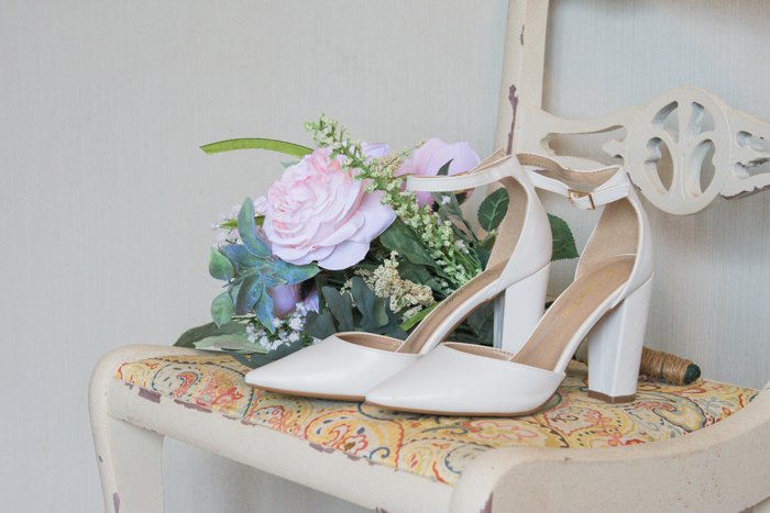 naturaleza muerta atmosférica de zapatos de boda y flores en una silla - consejos de negocios de fotografía de bodas